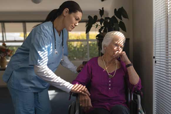 Nurse and sad woman in nursing home
